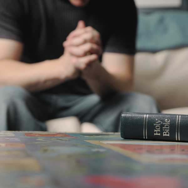 A man praying a dynamic prayer with a Bible on the table in front of him.